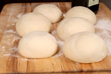 six balls of freshly made pizza dough on cutting board