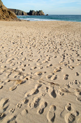 footprints on the beach at porthcurno, cornwall.