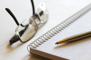 notebook, pen and eyeglasses
