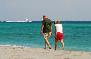 retired couple waling on beach
