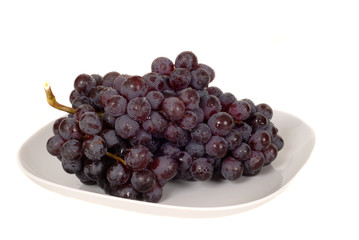 a bunch of juicy red grapes on a white plate
