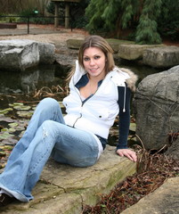 beautiful girl sitting on a rock next to water