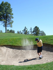 young golfer successfully hitting golf ball out of