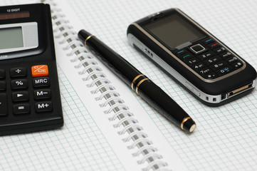calculator, ballpen and mobile phone on the notebook