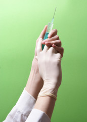 syringe in hands on green