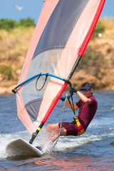 man in wetsuit on fastmoving windsurfer