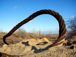 thick rusty wire rope and ring in sand