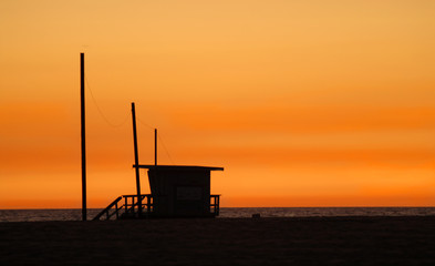 a lifeguard shack on a beach against a golden sunset