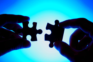hands joining two puzzle pieces.