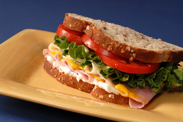 ham, cheese, lettuce and tomato sandwich on yellow plate