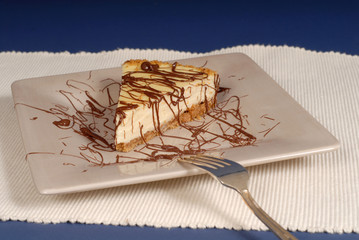 a piece of cheesecake with chocolate drizzled over it