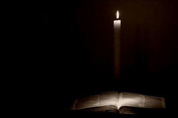 holy bible lit by a candle