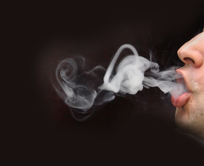 man blowing smoke with black background