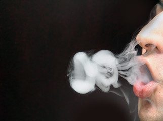 closeup of man blowing smoke with black background
