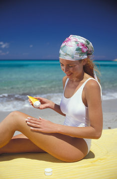 donna si mette la crema al mare