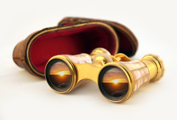 isolated antique case and gold binoculars with sunset reflection