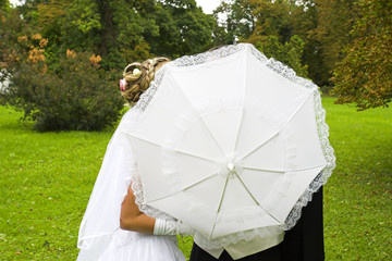 wedding kiss behind umbrella