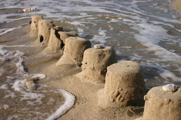 the ruins of a sand castle being swept away by the
