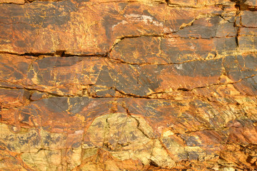 orange colored shoreline cliff face rock surface.