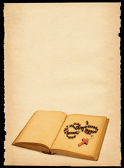 torn out old sheet of paper with book and rosary