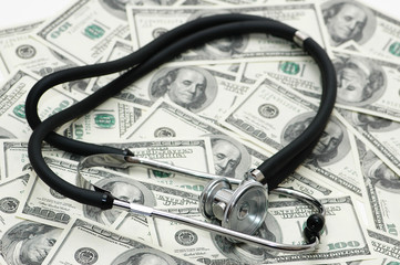 medical concept - stethoscope over the dollar bill