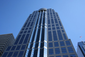 Fototapeta na wymiar looking up at tall modern skyscraper with blue sky