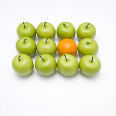 lots of crispy green apples with one orange in between