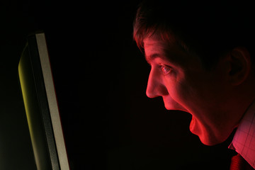 man screaming at red computer monitor