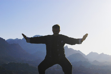Man tai chi silhouette in the mountains.