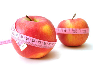 apples with pink tape measure over white background (concept of