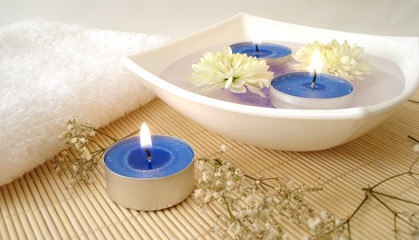 spa essentials (white towel, blue candles and flowers in water)