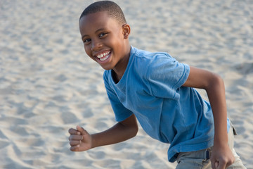boy running with sand on the beach