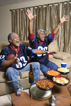 middle-aged african-american couple watching sports on tv.