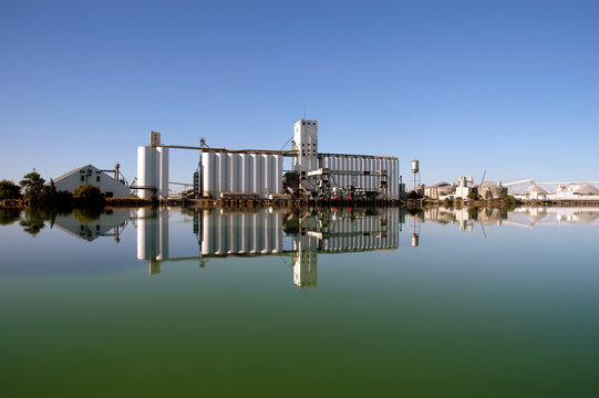 grain silo reflected in green water