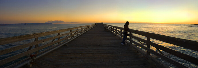 woman on a pier during sunset