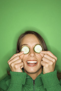 Young Caucasian Woman Holding Cucumber Slices Over Her Eyes.