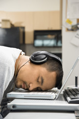 man with headphones sleeping on laptop.