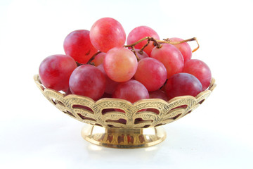 gold fruit dish with red grapes