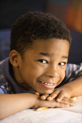 Young boy with head on hands with book in front.