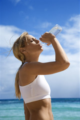 Woman drinking water on beach.
