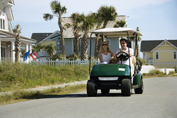 Dad driving golf cart with mom beside him.