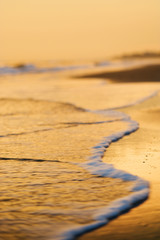 Fototapeta na wymiar Fale docierania na plaży o zachodzie słońca.