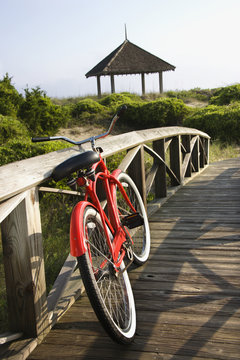 Red bike leaned up against wooden railing.