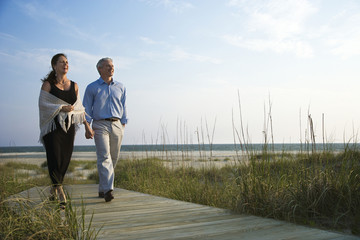 Couple holding hands on coastal walkway.