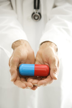 doctor holding out an oversized pill.