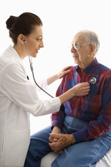 doctor listening to elderly man's heart with stethoscope.