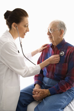 Doctor Listening To Elderly Man's Heart With Stethoscope.