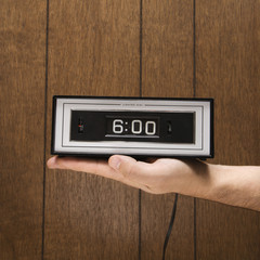 hand holding retro clock set for 6:00.