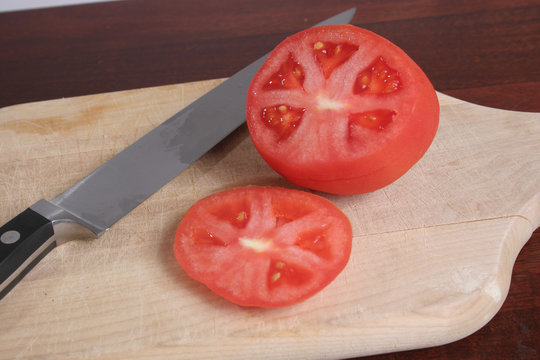 tomatos with knife on a wooden cuttingboard