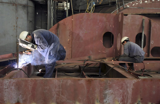 Welders with protective mask welding metal at double bottom ship in a shipyard